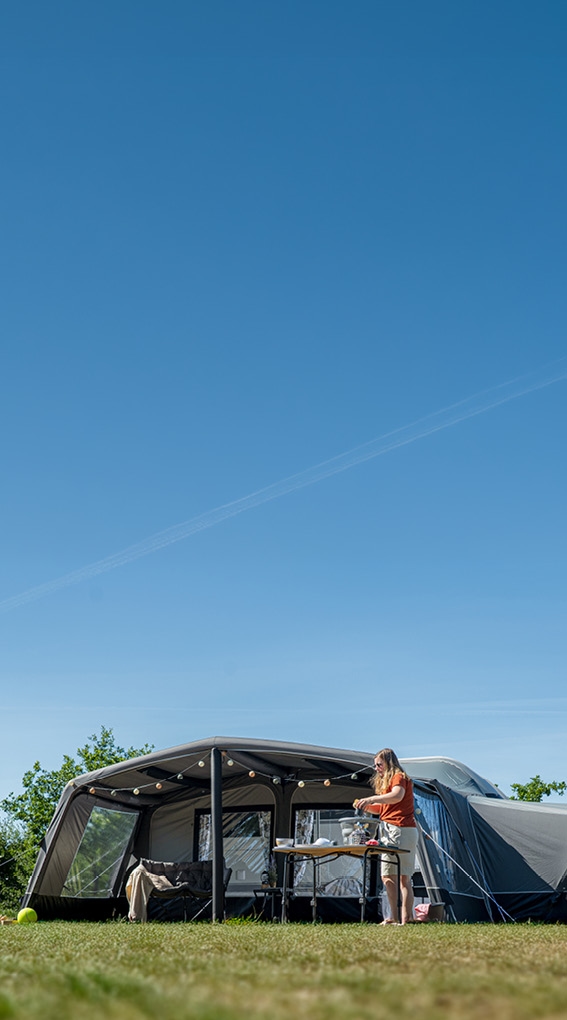Camper-Vorzelt mit Outdoor-Küche unter sonnigem Himmel