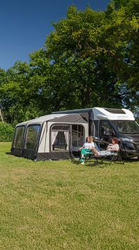 Wohnmobil mit Vorzelt auf grüner Campingwiese im Sommer
