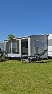 Wohnwagen mit Markise auf sonnigem Campingplatz
