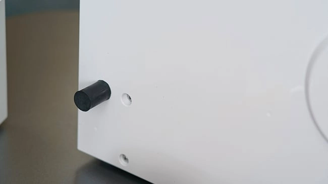 Schritt 2a wie montiert man eine Split-Klimaanlage Nahaufnahme eines weißen elektronischen Geräts mit einem schwarzen Knopf oder Anschluss an der Seite vor einem neutralen Hintergrund.