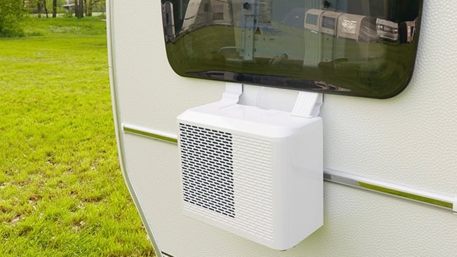 Schritt 6 wie montiert man eine Split-Klimaanlage Weiße Klimaanlage an der Außenseite eines Wohnwagens auf einem grünen Campingplatz montiert